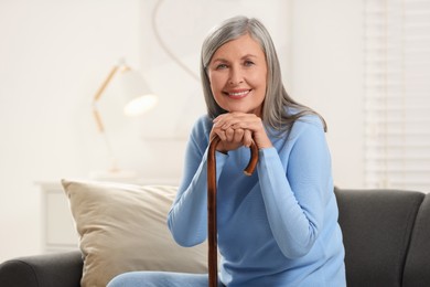 Mature woman with walking cane on sofa at home