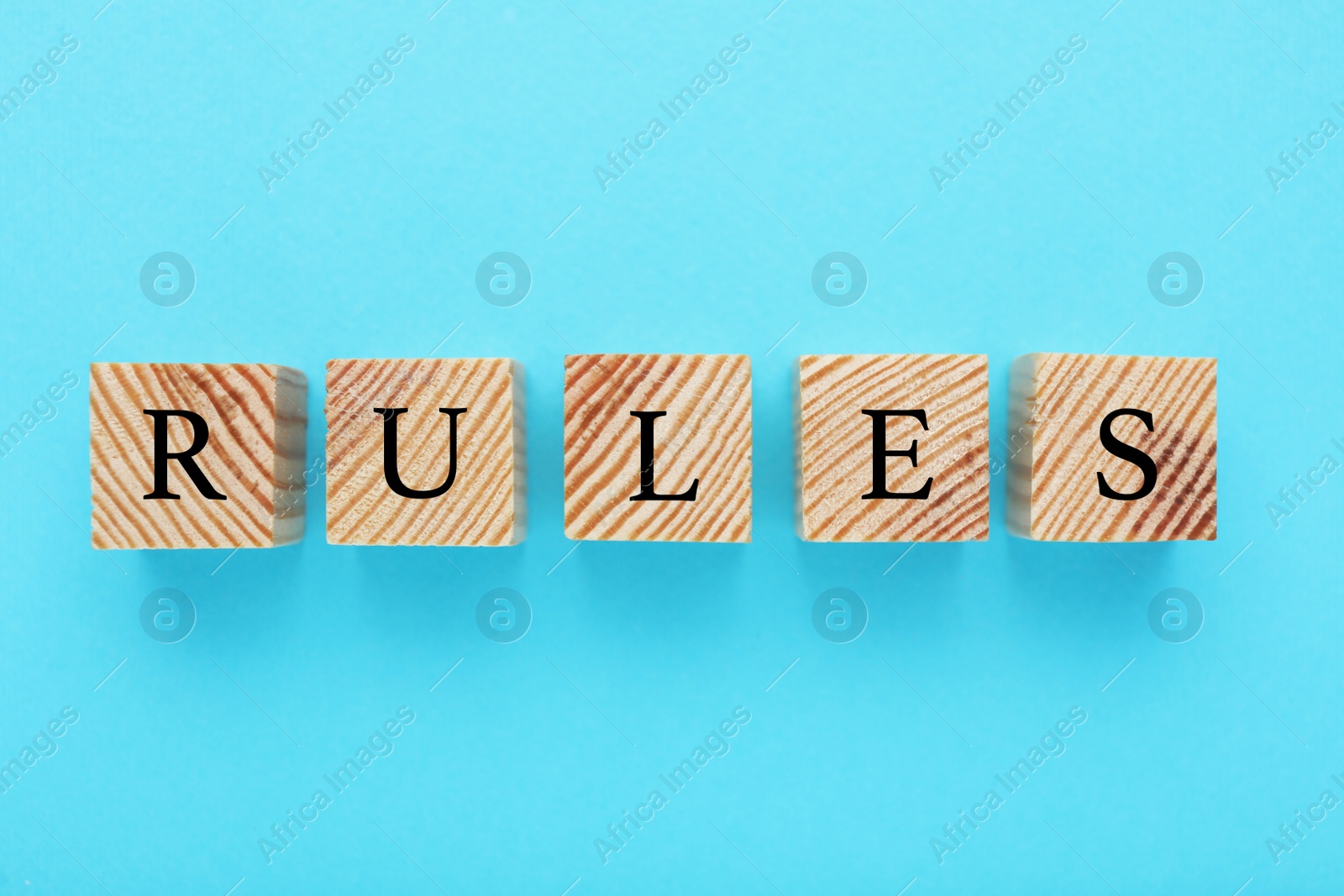 Photo of Word Rules made of wooden cubes with letters on light blue background, flat lay