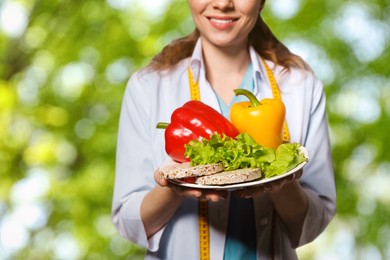 Image of Nutritionist with healthy products on blurred green background, closeup