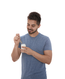Happy young man with yogurt and spoon on white background
