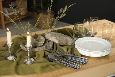 Photo of Clean dishes, stones and plants on wooden table in stylish dining room