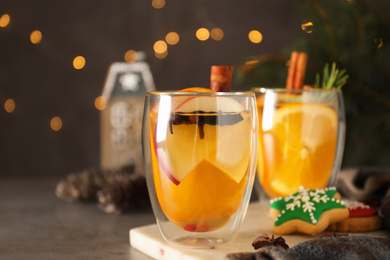 Photo of Aromatic white mulled wine on grey table against blurred lights