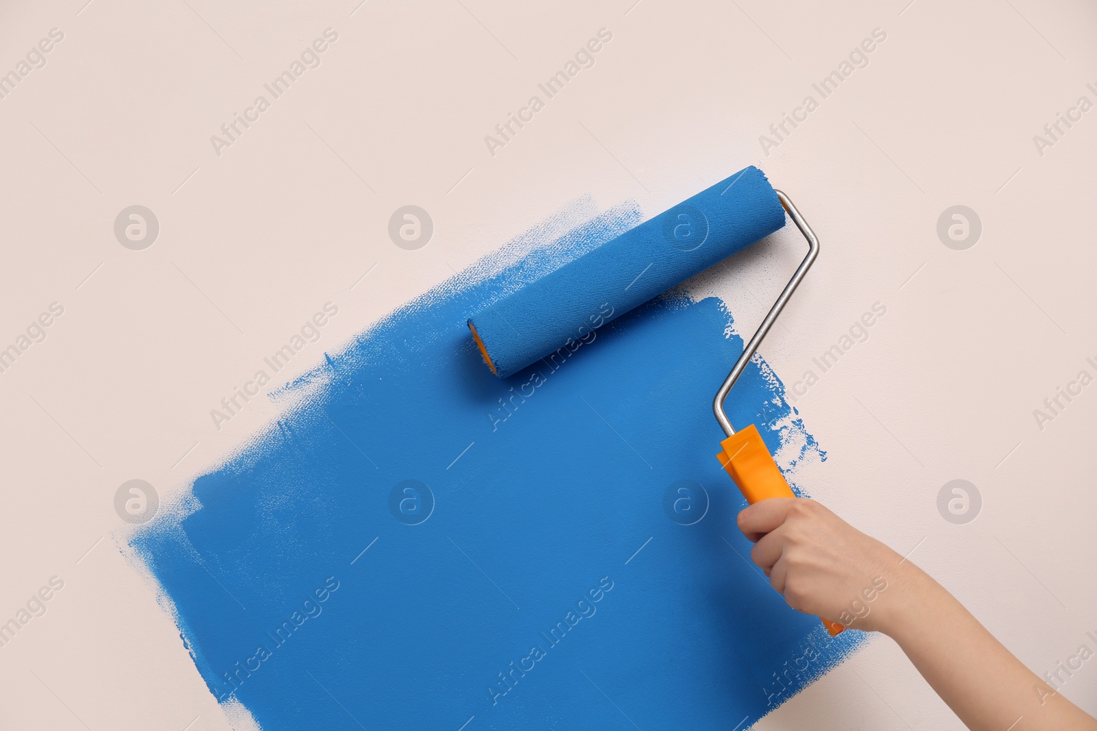 Photo of Woman painting wall with roller, closeup. Redecoration