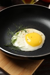 Photo of Delicious fried egg in frying paan on wooden table, closeup