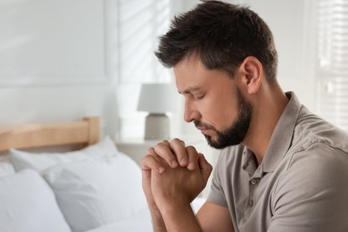 Photo of Religious man praying in bedroom. Space for text