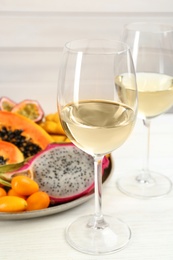 Photo of Delicious exotic fruits and wine on white wooden table