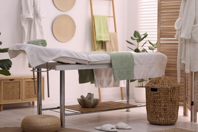 Photo of Comfortable massage table with clean towels in spa center