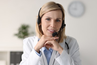 Photo of Smiling doctor wearing headphones having online in office