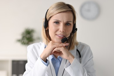 Smiling doctor wearing headphones having online in office