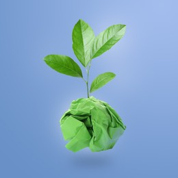 Image of Crumpled sheet of paper on twig with green leaves on light blue background. Recycling concept