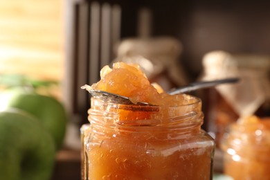 Photo of Jar with delicious apple jam against blurred background, closeup
