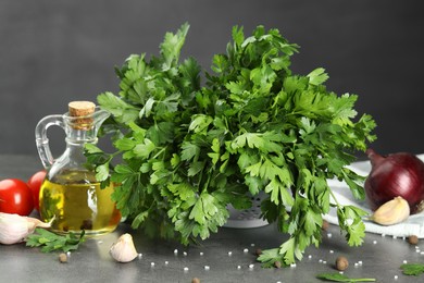 Photo of Fresh parsley, oil and other products on grey table