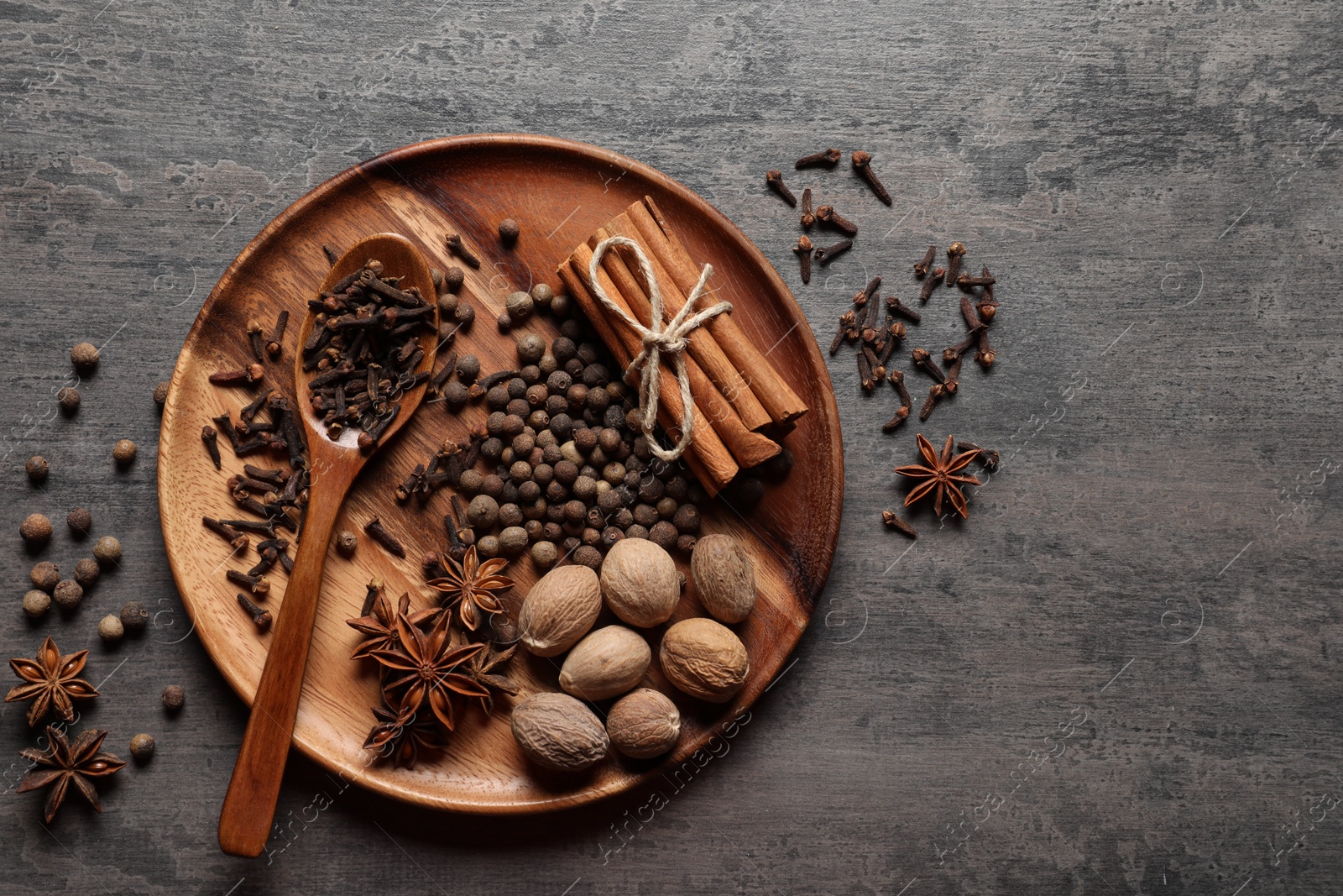 Photo of Different spices and nuts on gray textured table, top view. Space for text