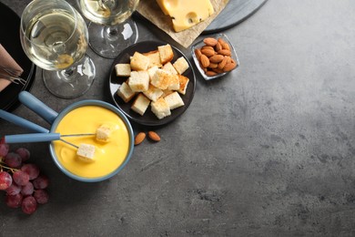 Photo of Flat lay composition with pot of tasty cheese fondue on grey table. Space for text