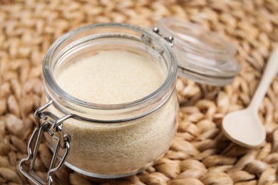 Photo of Gelatin powder in glass jar on wicker mat, closeup