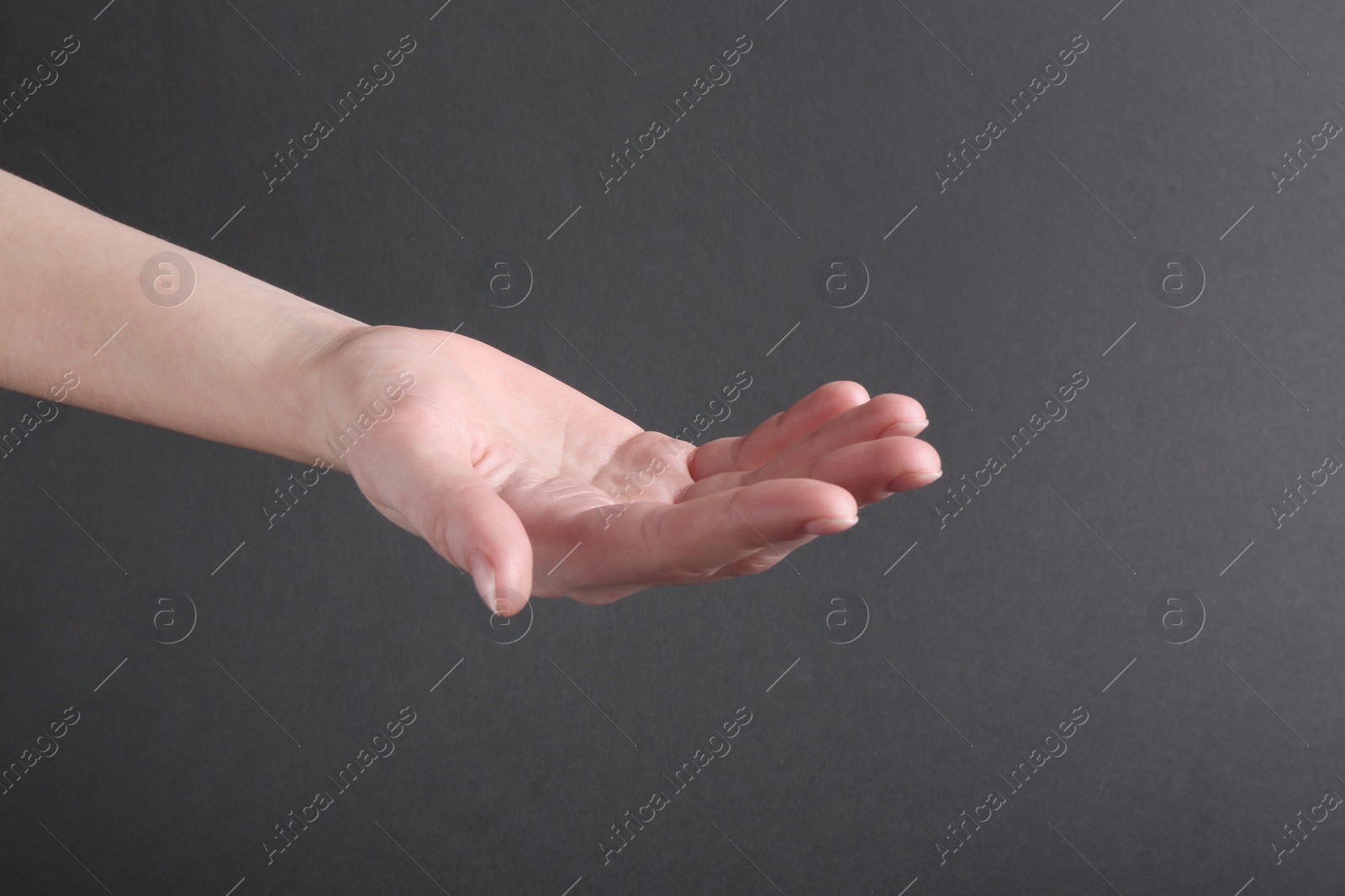 Photo of Woman holding hand on black background, closeup