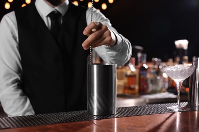 Bartender preparing fresh alcoholic cocktail at bar counter, closeup