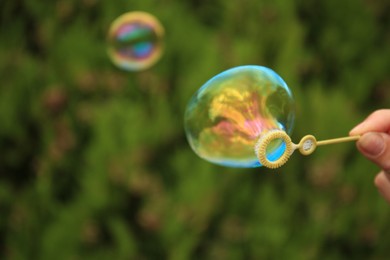 Photo of Woman blowing beautiful soap bubbles outdoors, closeup. Space for text