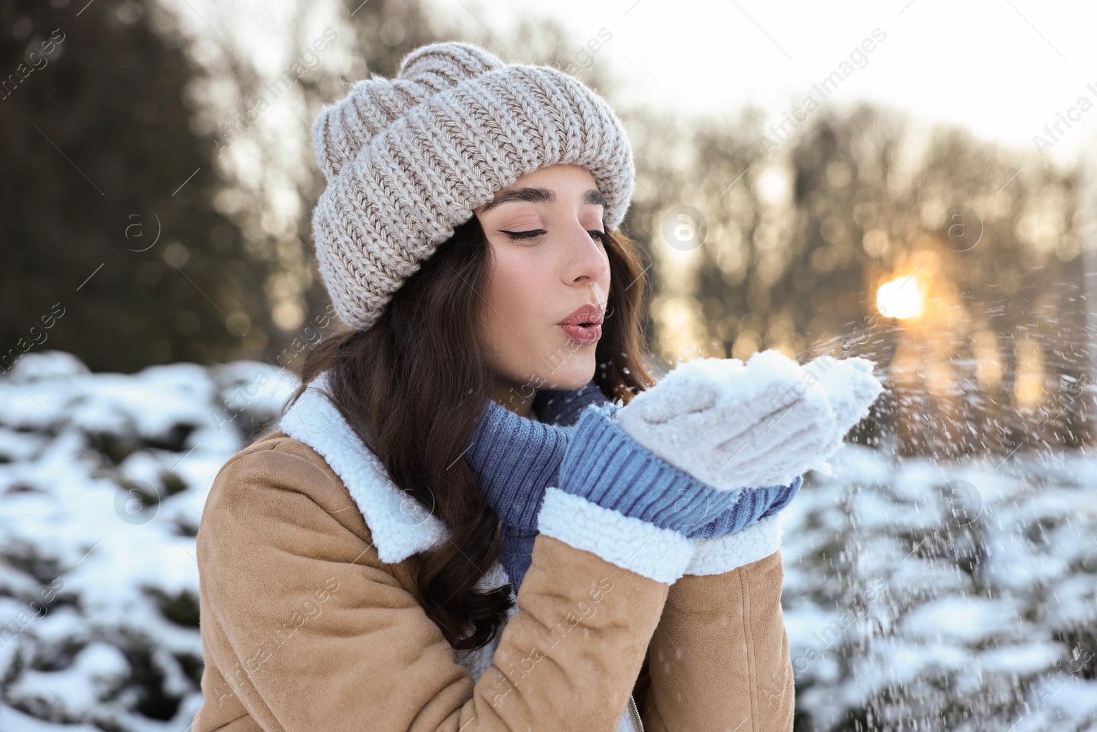 Photo of Portrait of beautiful woman blowing snow from hands in park