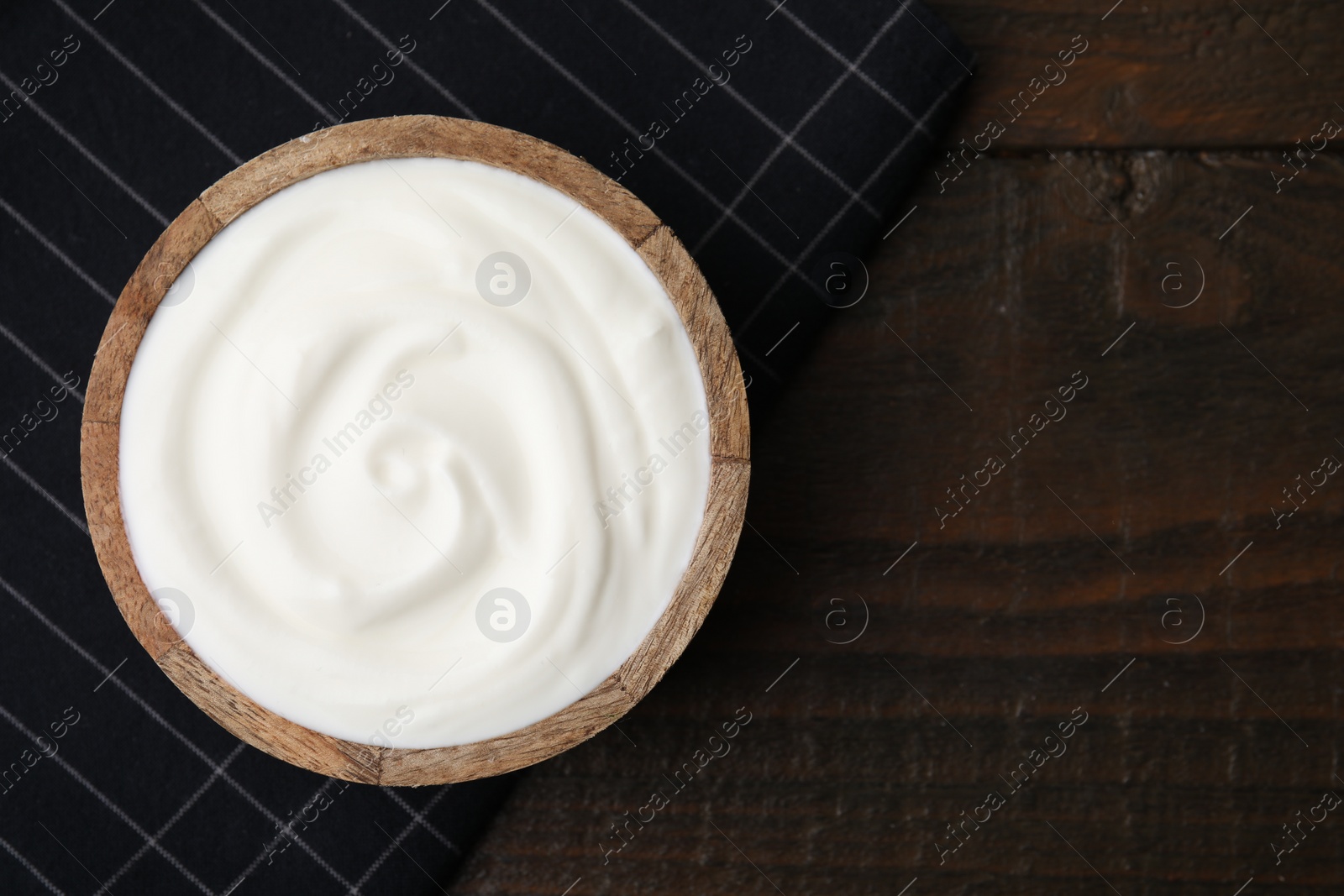 Photo of Delicious natural yogurt in bowl on wooden table, top view