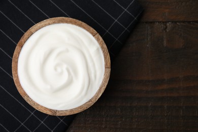 Delicious natural yogurt in bowl on wooden table, top view