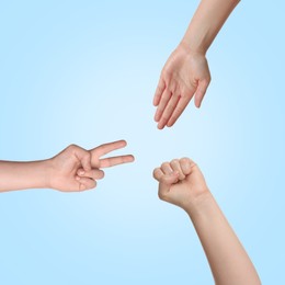 People playing rock, paper and scissors on light blue background, top view