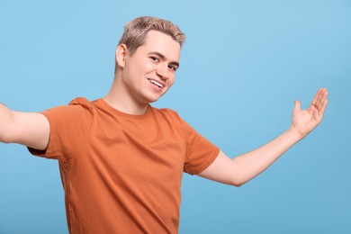 Happy man inviting to come in against light blue background