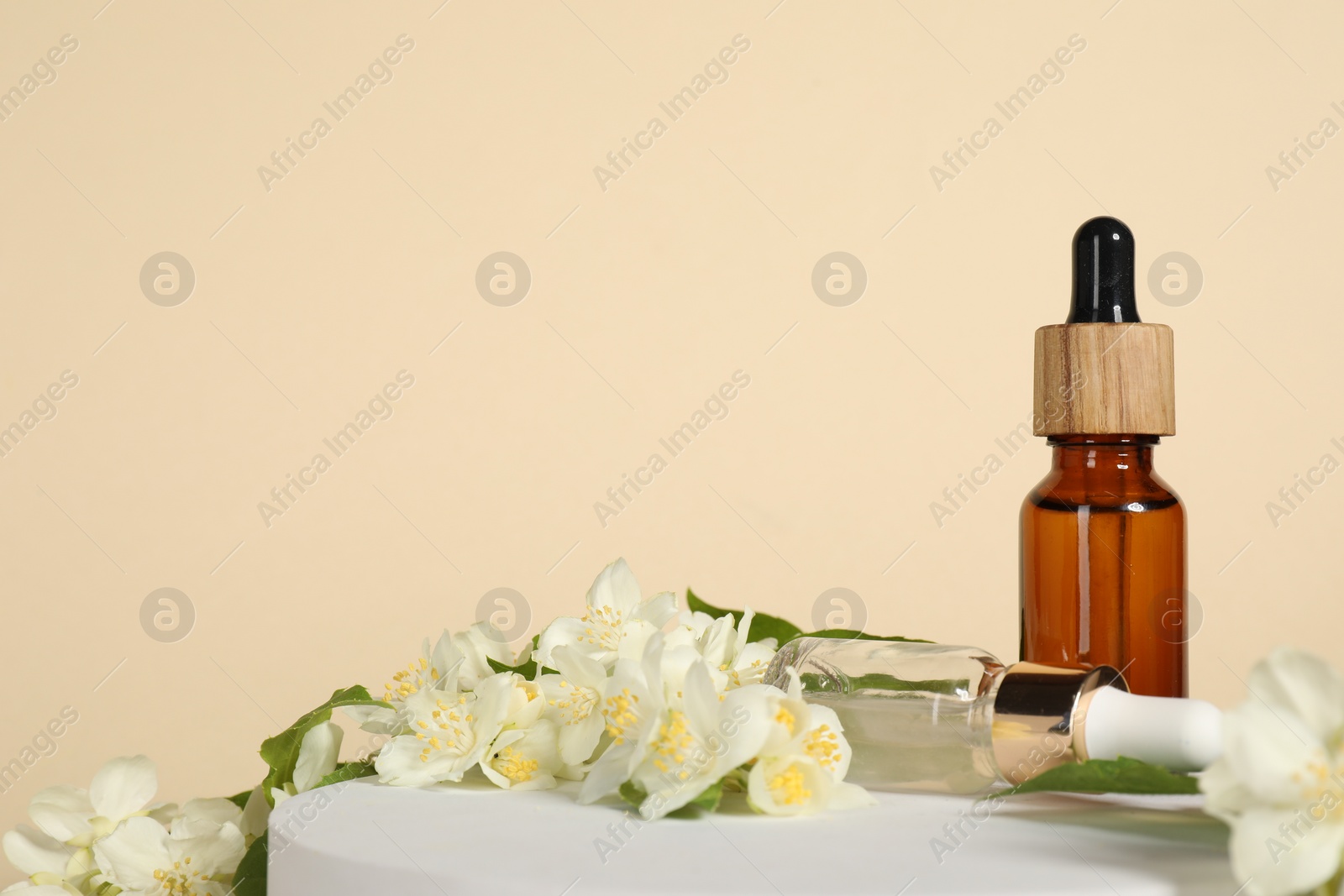 Photo of Presentation of essential oils in bottles and beautiful jasmine flowers against beige background