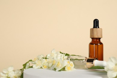 Presentation of essential oils in bottles and beautiful jasmine flowers against beige background