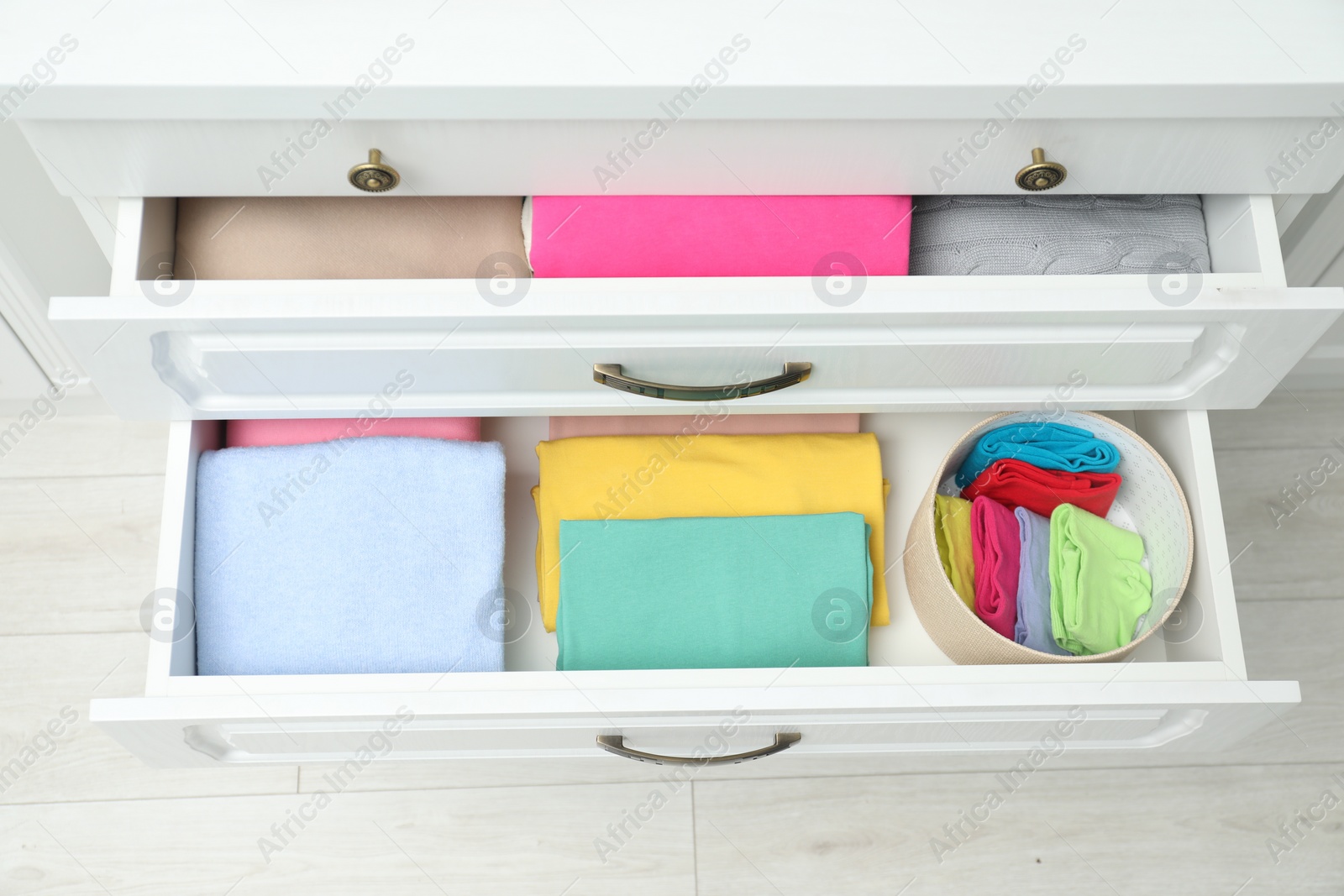 Photo of Chest of drawers with different folded clothes indoors, top view