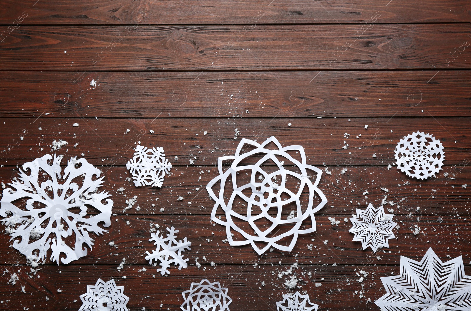 Photo of Flat lay composition with paper snowflakes on wooden background, space for text. Winter season