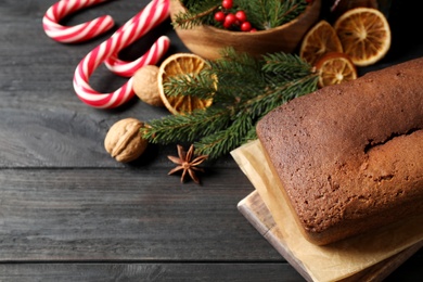Photo of Delicious gingerbread cake and Christmas items on black wooden table, above view
