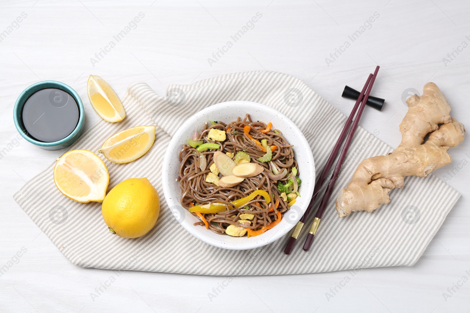 Photo of Stir-fry. Delicious cooked noodles with chicken and vegetables in bowl served on light wooden table, flat lay