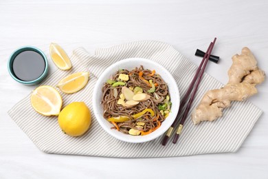 Photo of Stir-fry. Delicious cooked noodles with chicken and vegetables in bowl served on light wooden table, flat lay