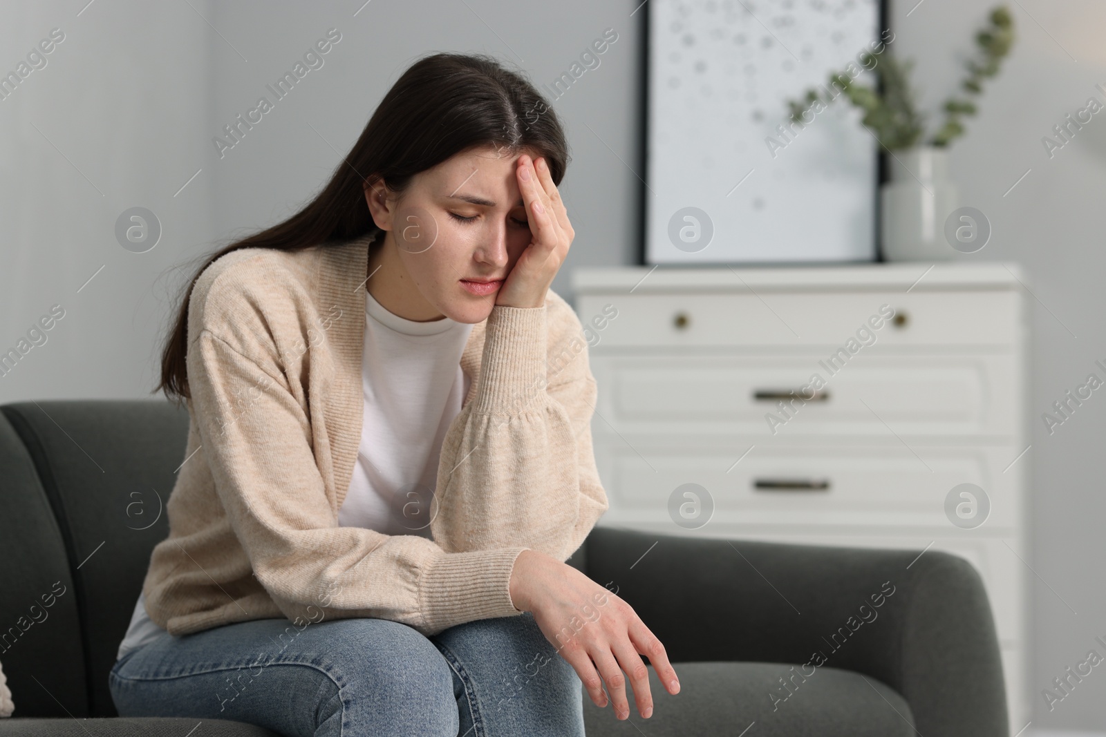 Photo of Overwhelmed woman sitting on sofa at home