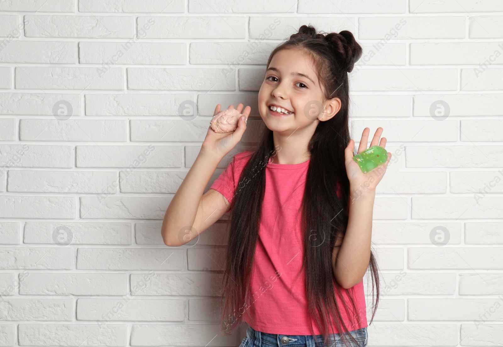 Photo of Little girl with slime near white brick wall