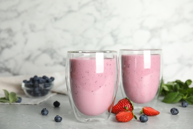 Photo of Tasty milk shakes and fresh berries on grey marble table