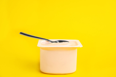 Tasty organic yogurt in plastic cup on yellow background