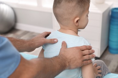 Orthopedist examining child's back in clinic, closeup. Scoliosis treatment