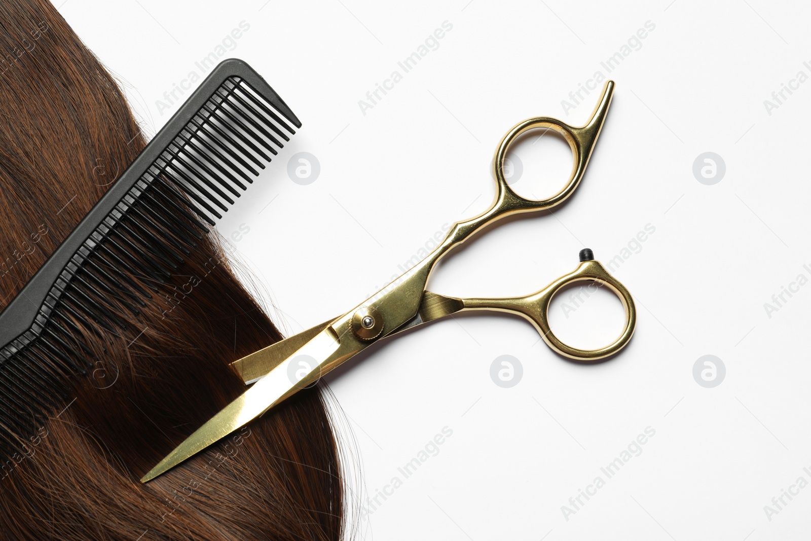 Photo of Professional hairdresser scissors and comb with brown hair strand on white background, flat lay