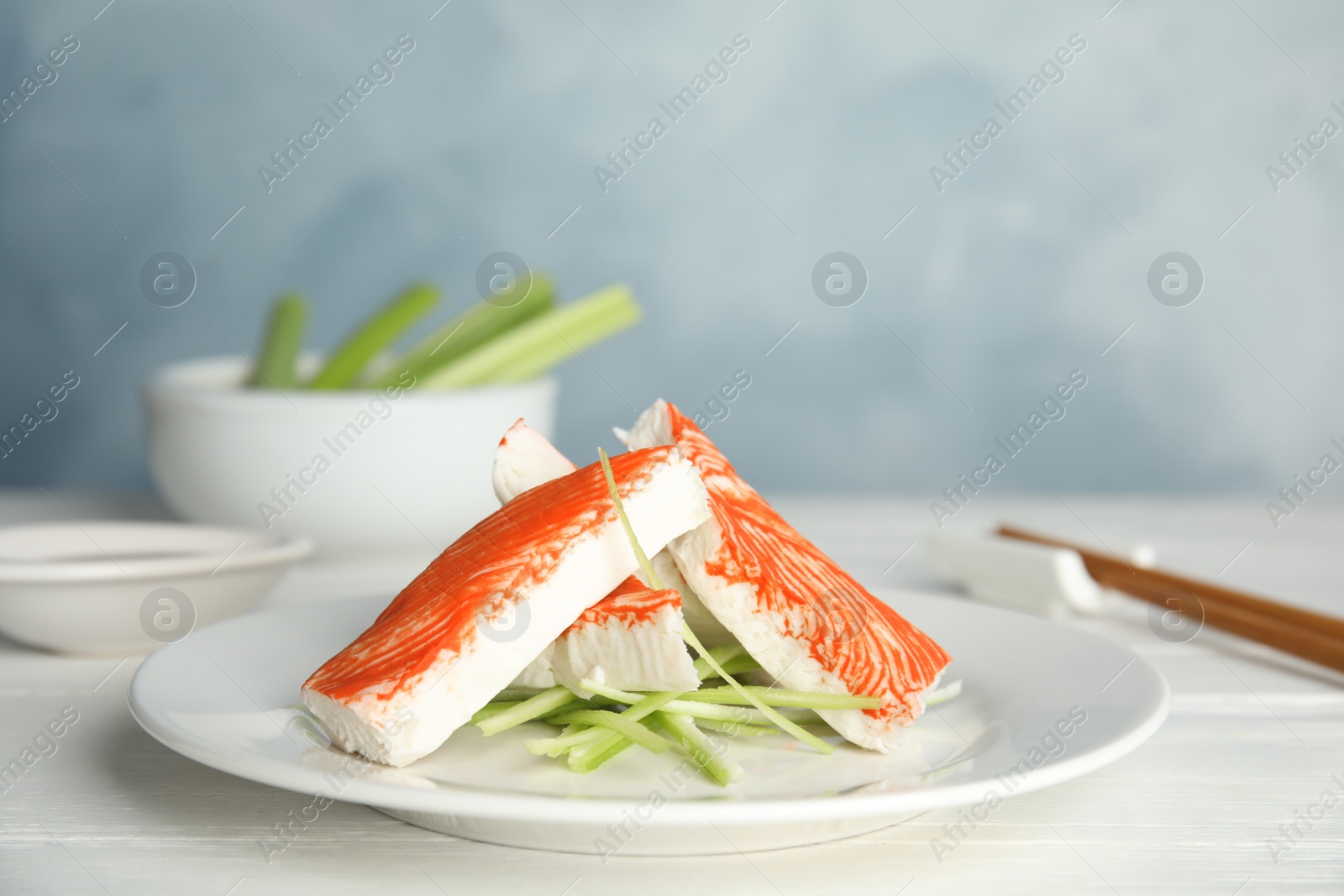 Photo of Fresh crab sticks with cucumber served on white wooden table
