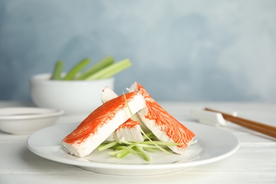 Photo of Fresh crab sticks with cucumber served on white wooden table