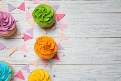 Photo of Colorful birthday cupcakes on white wooden table, flat lay. Space for text