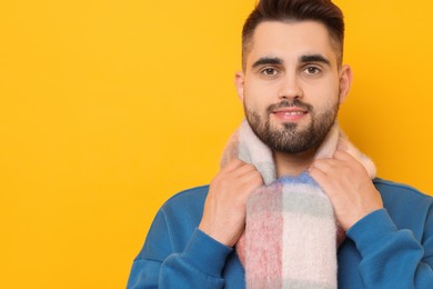 Photo of Smiling man in warm scarf on yellow background. Space for text