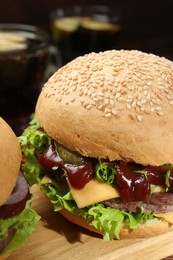 Photo of Wooden board with delicious cheeseburgers against blurred background, closeup