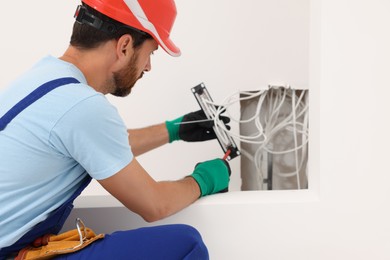 Photo of Electrician with screwdriver fixing patch panel indoors