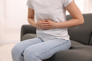 Photo of Woman suffering from abdominal pain indoors, closeup. Unhealthy stomach