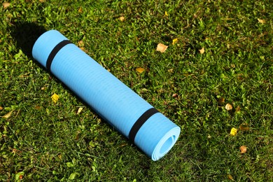 Bright karemat or fitness mat on fresh green grass outdoors, above view. Space for text