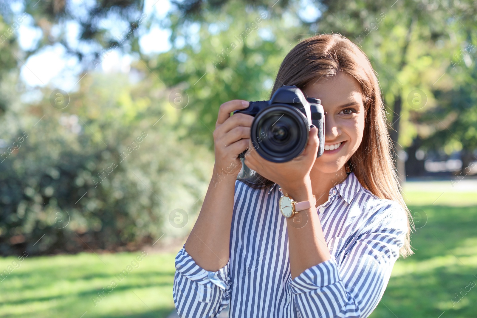 Photo of Young female photographer with professional camera in park. Space for text