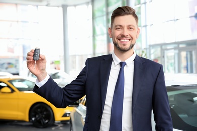 Businessman with key in dealership. Buying new car